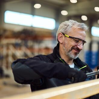 Mature Worker Using Tools in Industrial Workshop Setting with Focus and Concentration